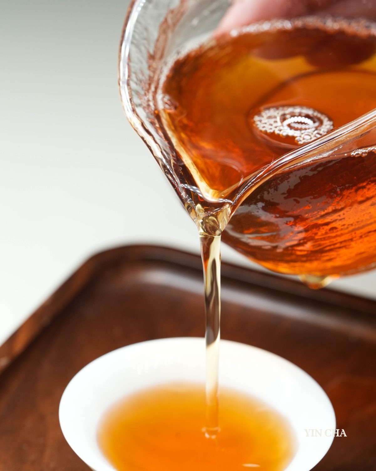 Earthy Hóng Dianhong black tea being poured from a glass teapot into a white cup