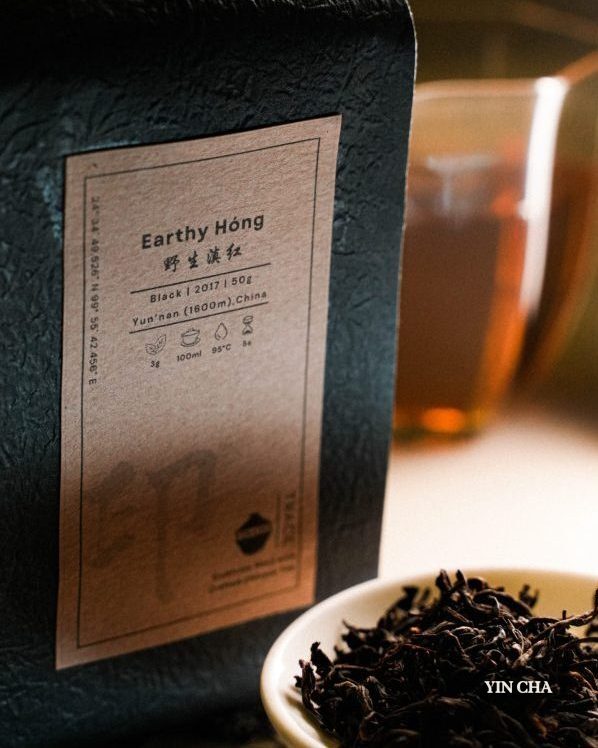 Earthy Hóng Dianhong tea packaging with loose tea and brewed tea in the background