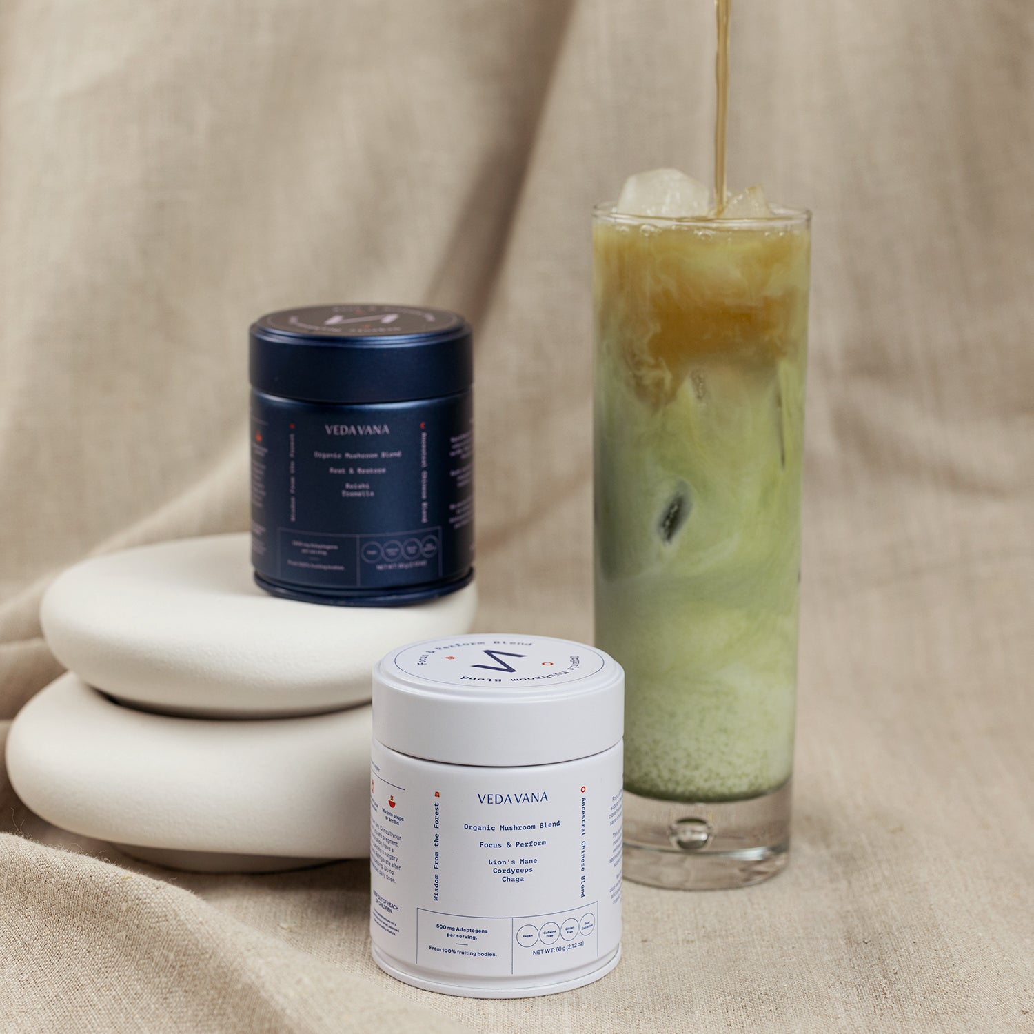 Vedavana Focus and Restore mushroom blends with iced layered tea drink on fabric background