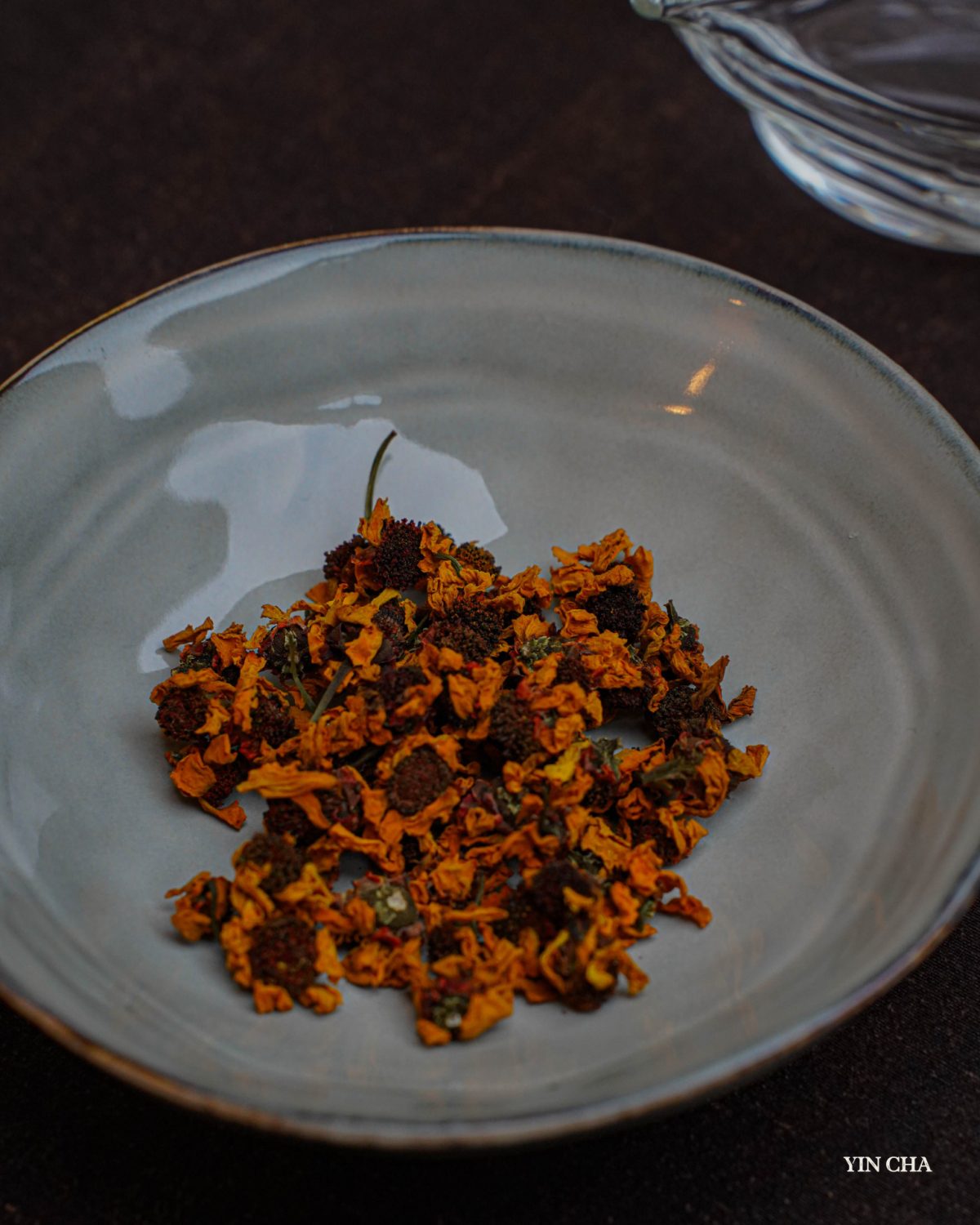 Loose dried Snow Chrysanthemum tea flowers in a white bowl with Yin Cha branding
