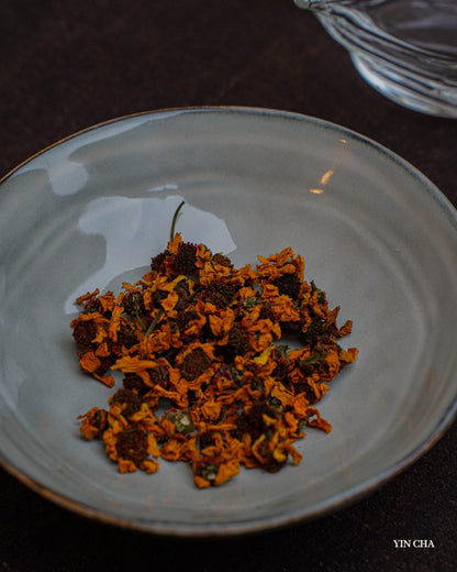 Loose dried Snow Chrysanthemum tea flowers in a white bowl with Yin Cha branding