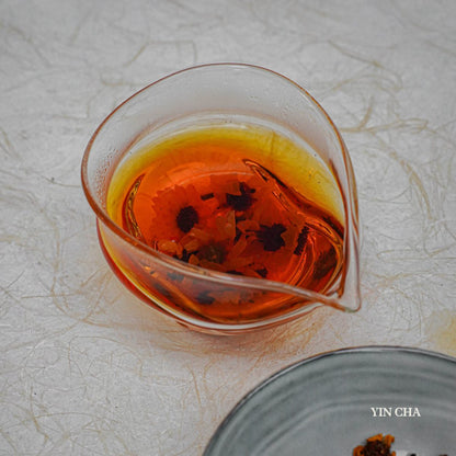 Brewed Snow Chrysanthemum tea in a glass teapot on a textured white background