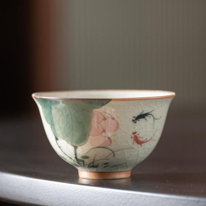 Handcrafted Dehua porcelain teacup with lotus and koi fish design, crackled glaze finish.