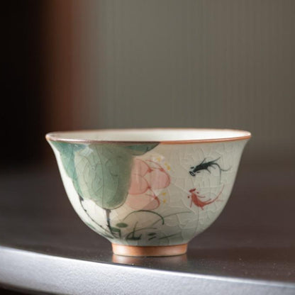 Handcrafted Dehua porcelain teacup with lotus and koi fish design, crackled glaze finish.