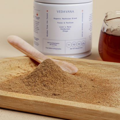 Close-up of organic mushroom extract powder from Vedavana with wooden spoon and tea in background